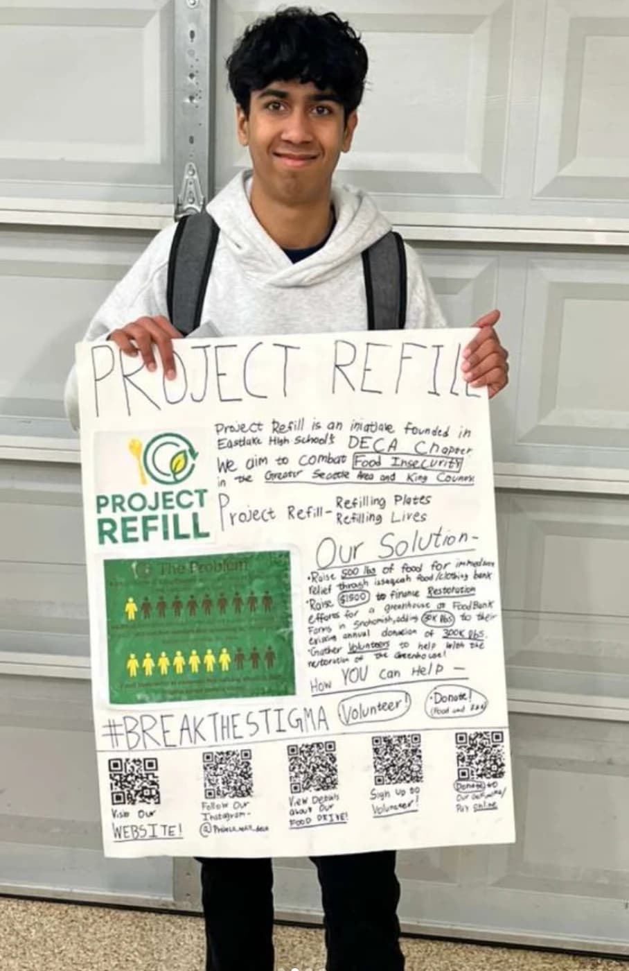 Project Refill founder holding the Project Refill poster outside a garage during the fundraiser